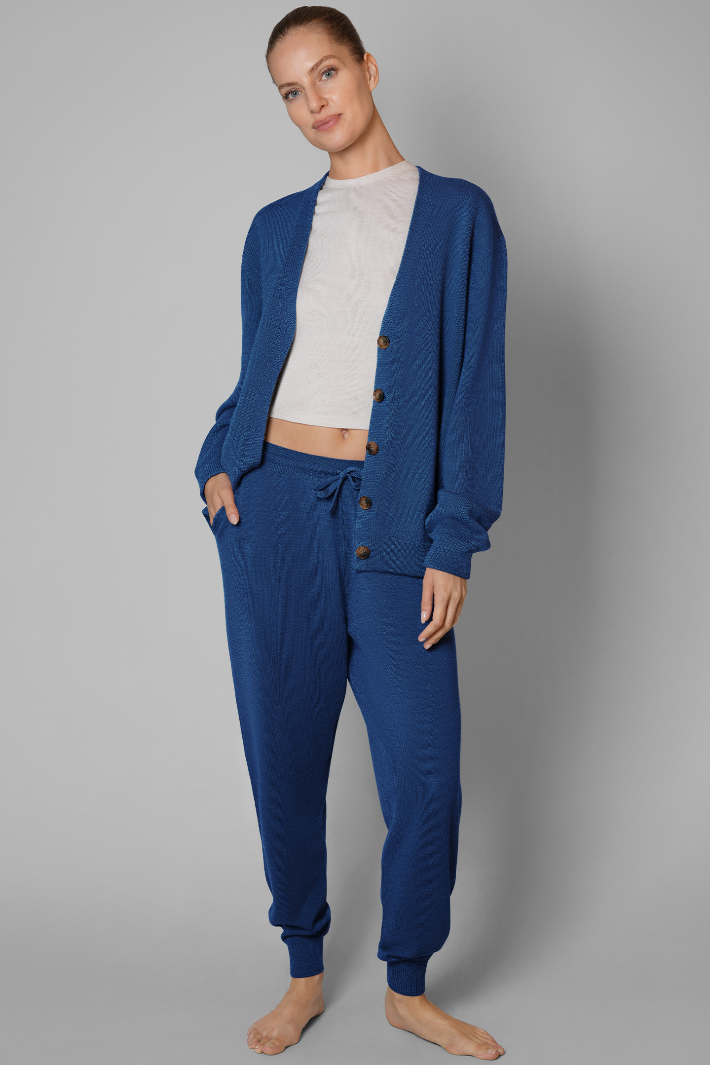 Woman wearing a blue cardigan and pants set on a gray background