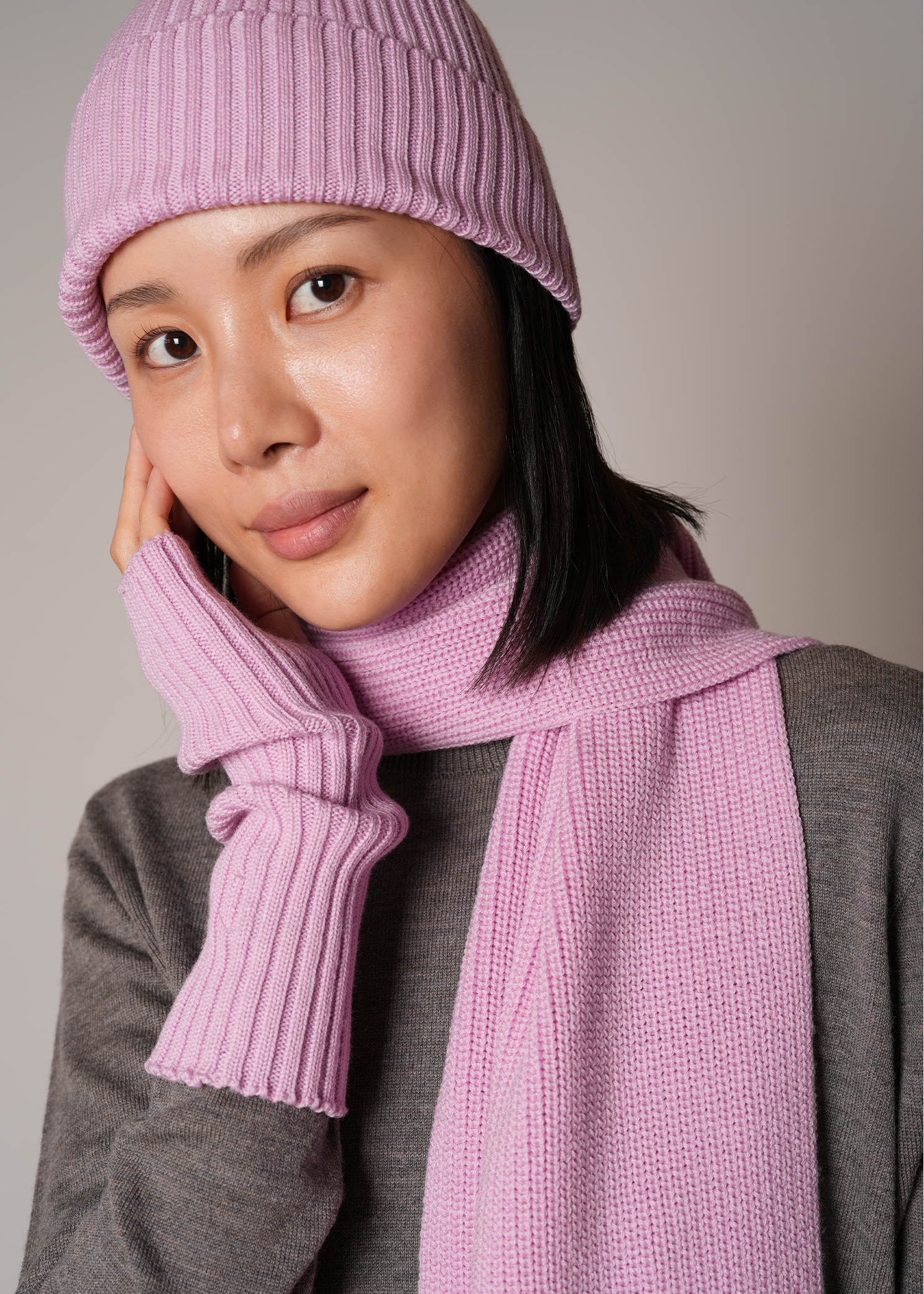 Person wearing a pink knit hat and scarf against a plain background